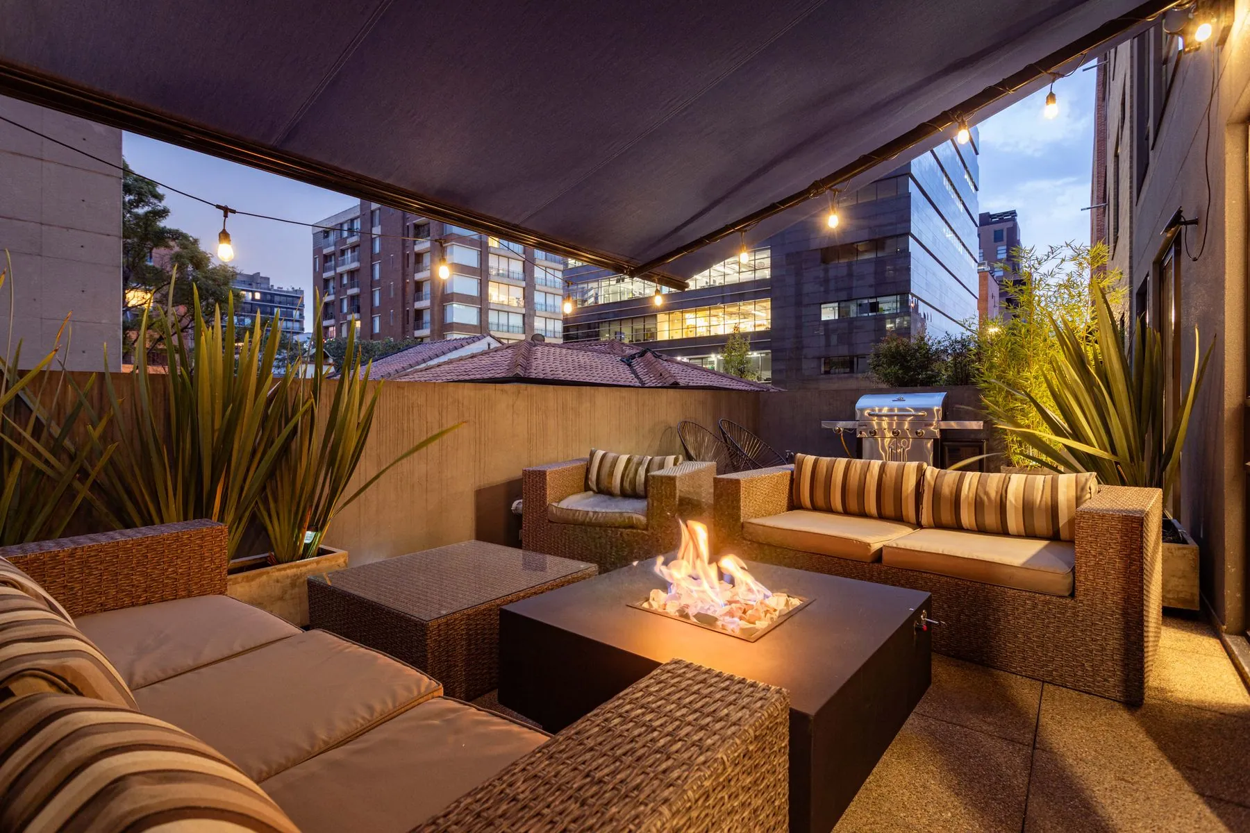 An outdoor lounge with a fire table at dusk